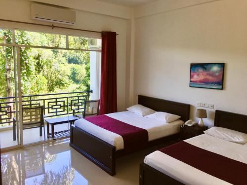 a hotel room with two beds and a balcony at Kandy Rivers Edge Nature Resort in Kandy