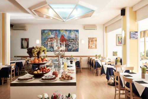 una sala da pranzo con tavoli e sedie e un dipinto sul muro di Hotel Villa Roma a Caorle