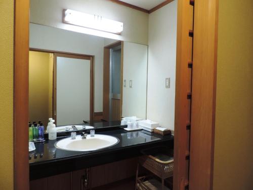 a bathroom with a sink and a large mirror at Konjakutei in Aizuwakamatsu
