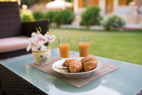 a table with a plate of food and two glasses of orange juice at Dallas Valtos Studios in Parga