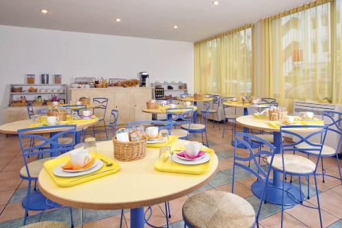 une cafétéria avec des tables et des chaises et de la vaisselle dans l'établissement Séjours & Affaires Lyon Saint-Nicolas, à Lyon