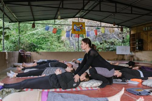 - un groupe de personnes se posant au sol dans un cours de yoga dans l'établissement Rishikesh Valley, à Rishikesh