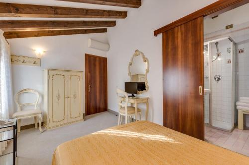 a bedroom with a bed and a desk and a bathroom at Hotel Bernardi Semenzato in Venice