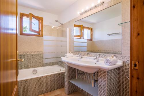 een badkamer met een wastafel, een bad en een spiegel bij Finca Xemarri in Santanyi