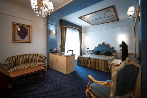 een slaapkamer met een bed, een bank en een stoel bij Bonotto Hotel Belvedere in Bassano del Grappa