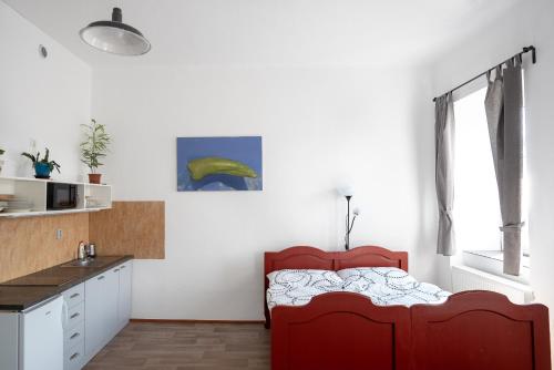 a bedroom with a red bed and a kitchen at Apartmány16 Olešnice v Orlických horách in Olešnice v Orlických horách