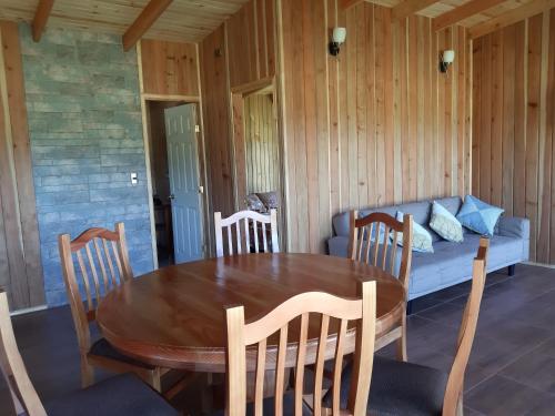a dining room with a table and a couch at Paraíso Liumalla Lodge in Villarrica
