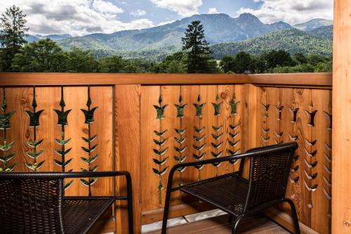 a chair on a wooden deck with mountains in the background at Royal Hill Residence in Zakopane