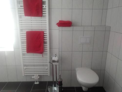 uma casa de banho com um WC branco e toalhas vermelhas em Bike Pension Knausz em Pöls