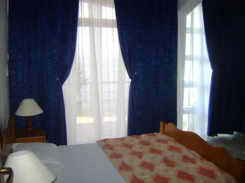 a bedroom with blue curtains and a bed and a window at Arabela Apartments in Utjeha