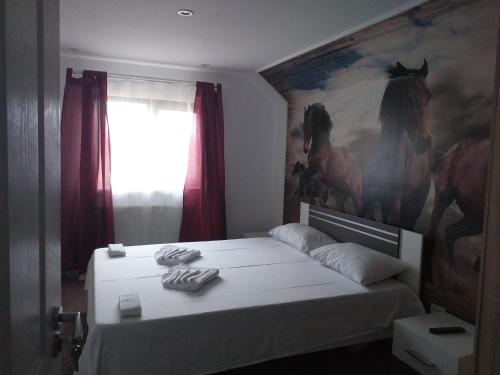 a bedroom with a bed with a painting of horses on the wall at Hotel Hobby in Hunedoara
