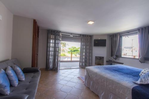 1 dormitorio con cama, sofá y ventana en Costa Terral Hostel Beach Fun en Matinhos