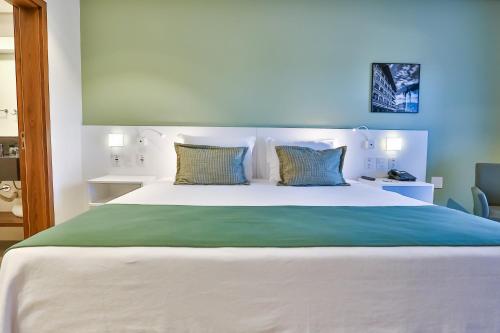 a bedroom with a large white bed with two pillows at Quality Hotel Blumenau in Blumenau