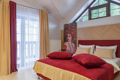 Schlafzimmer mit einem großen roten Bett und einem großen Fenster in der Unterkunft Mal'ovanka in Bukowel
