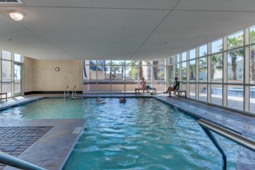 una gran piscina con personas sentadas en bancos en un edificio en Crystal Towers, en Gulf Shores