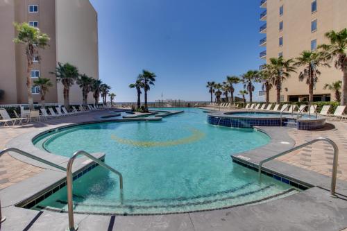 a large swimming pool with palm trees and buildings at Crystal Towers in Gulf Shores