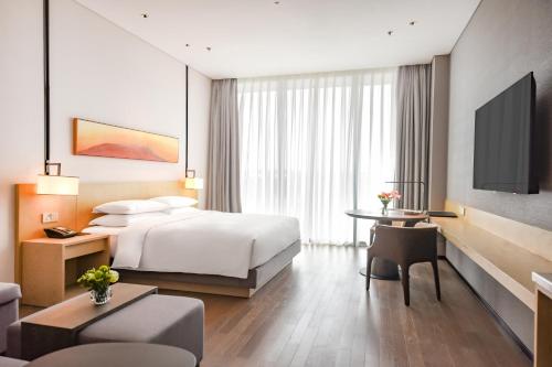 a hotel room with a bed and a desk and a tv at Hyatt Place Changsha Airport in Changsha