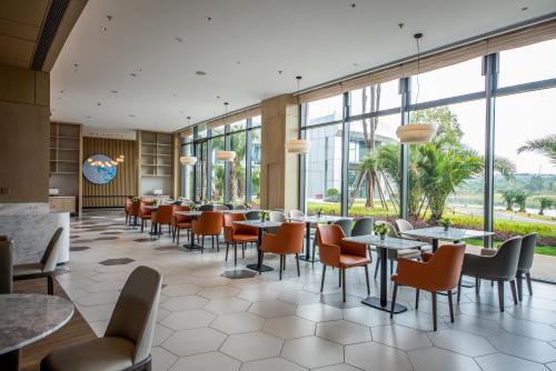 a restaurant with tables and chairs and windows at Hyatt Place Changsha Airport in Changsha