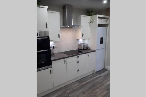 una cocina con armarios blancos y electrodomésticos negros en THE ANCHORAGE, en Arrochar