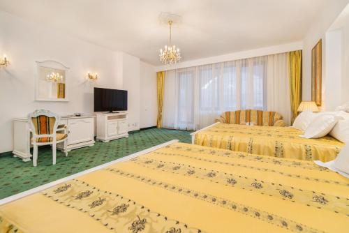 a hotel room with two beds and a television at Aurelius Imparatul Romanilor Hotel & SPA in Poiana Brasov