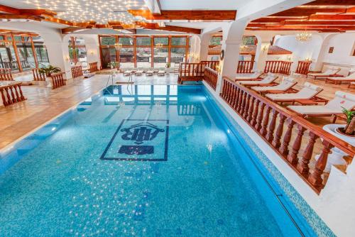 a pool in a hotel with chairs and tables at Aurelius Imparatul Romanilor Hotel & SPA in Poiana Brasov