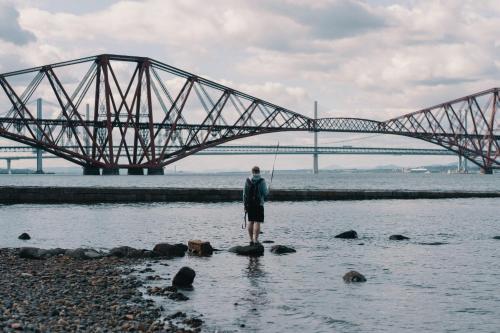 a man standing in the water in front of a bridge at Carvetii - Edward House B - 2 Dbl bed 1st floor flat in Dunfermline