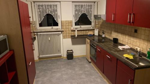 cocina con armarios rojos, fregadero y radiador en Ferienwohnung Schäfer, en Landwehrhagen