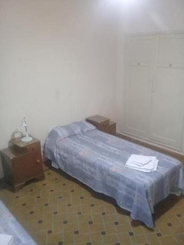 1 dormitorio con 1 cama con colcha azul y 2 mesas en casa a 2 cuadras de costanera carlos paz en Villa Carlos Paz