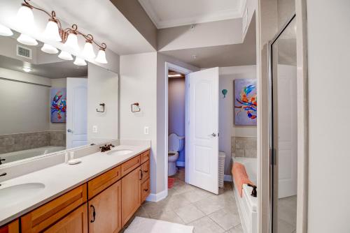 a bathroom with a sink and a toilet and a mirror at Sleek Gulfport Condo with Ocean Views and Pool Access! in Gulfport