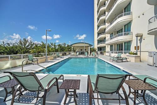 a swimming pool with chairs and a table and a building at Beachside Biloxi Club Condo Balcony with Ocean View in Biloxi