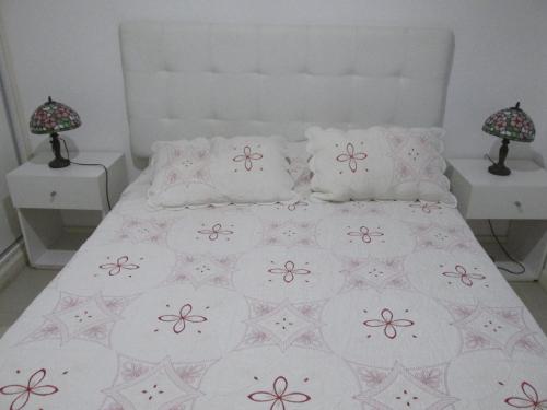 1 cama con colcha blanca y almohadas en Ayres del Puerto, en Punta del Este