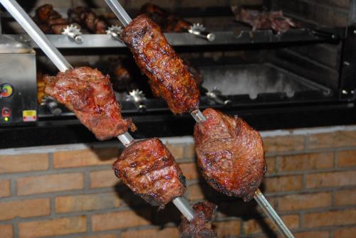 a bunch of meat on skewers being fried at Portal do Sol in Itaberaba