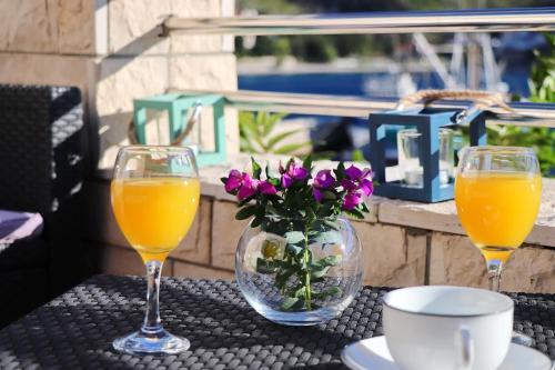 two glasses of orange juice and a vase of flowers on a table at Villa Silencia in Trstenik