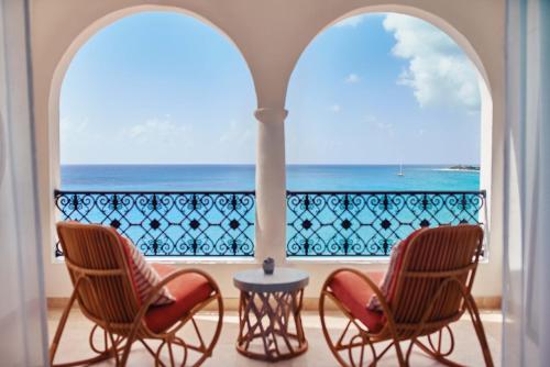 a balcony with two chairs and a view of the ocean at La Samanna, A Belmond Hotel, St Martin in Baie Longue