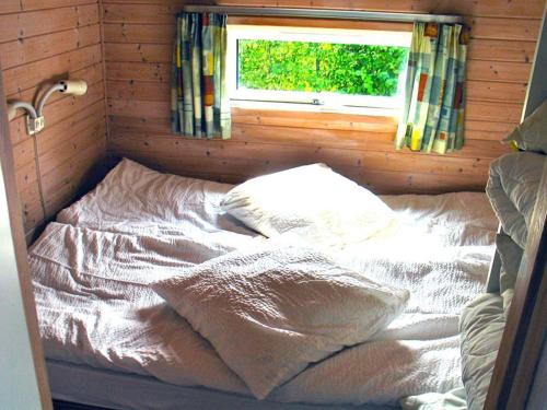 Bett in einem kleinen Zimmer mit Fenster in der Unterkunft Nakskov Fjord Camping & Cottages in Nakskov