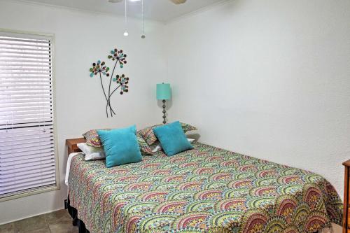 ein Schlafzimmer mit einem Bett mit blauen Kissen und einem Fenster in der Unterkunft Surfside Sandcastle Suite with Balcony and 2 Pools! in Corpus Christi