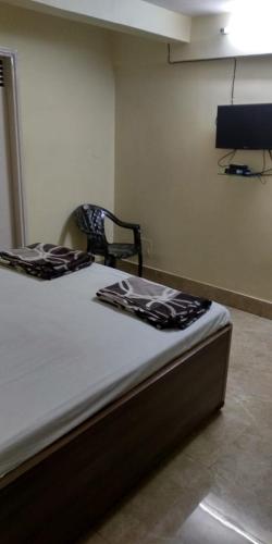 Cette chambre comprend un lit et une chaise. dans l'établissement Adarsh lodge, à Jamshedpur