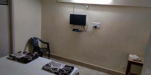 Habitación con cama y TV en la pared. en Adarsh lodge, en Jamshedpur