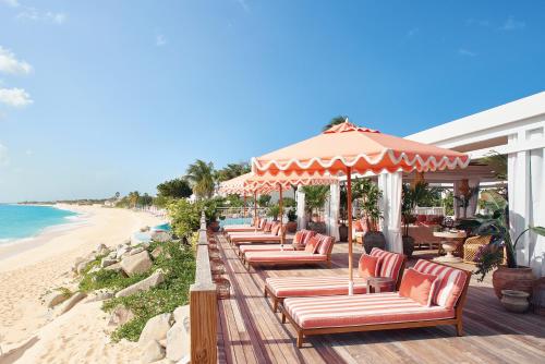 貝爾龍格的住宿－La Samanna, A Belmond Hotel, St Martin，海滩上的一排椅子和遮阳伞