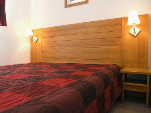 a hotel room with a bed and a wooden headboard at Résidence Les Toits du Dévoluy in Le Dévoluy