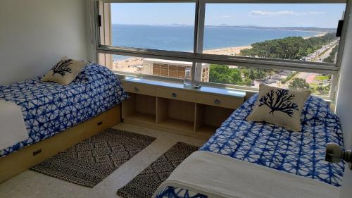 1 dormitorio con 2 camas y ventana grande en Amazing Oceanfront unit on Mansa Beach, en Punta del Este