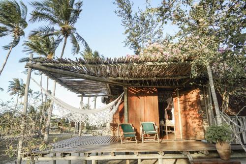 a house on the beach with chairs and palm trees at Rancho Do Peixe in Prea