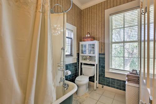 a bathroom with a toilet and a tub and a window at Historic Huntington Home with Pond and Flower Gardens! in Zavalla