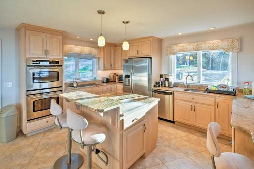 a kitchen with wooden cabinets and stainless steel appliances at Luxurious Oceanfront Flanders Bay Home with Kayaks! in Sullivan
