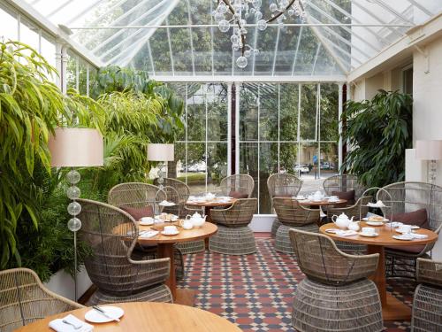 a restaurant with tables and chairs in a conservatory at Malmaison Cheltenham in Cheltenham