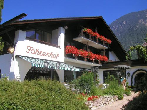 ein Gebäude mit roten Blumen auf dem Balkon in der Unterkunft Hotel Föhrenhof Garni in Farchant