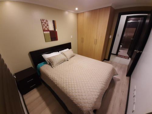 Un dormitorio con una cama grande con almohadas. en Condominio La Victoria, Departamento en Cuenca 1, en Cuenca