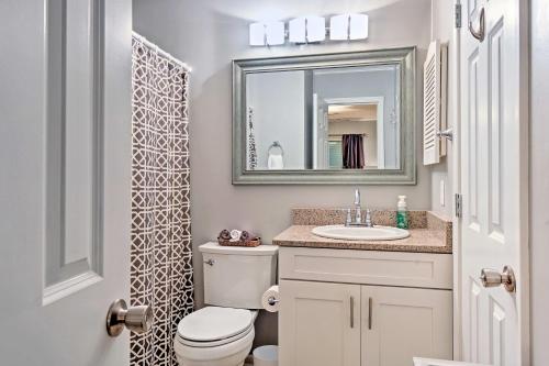 a bathroom with a toilet and a sink and a mirror at Hilton Head Resort Condo with Pool and Beach Access in Hilton Head Island