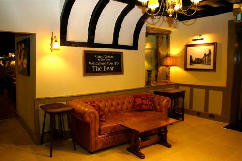 a couch in a room with a sign on the wall at The Bear Hotel by Greene King Inns in Hungerford