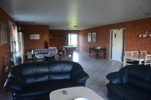 a living room with black leather furniture and a table at Paarup Kro in Engesvang